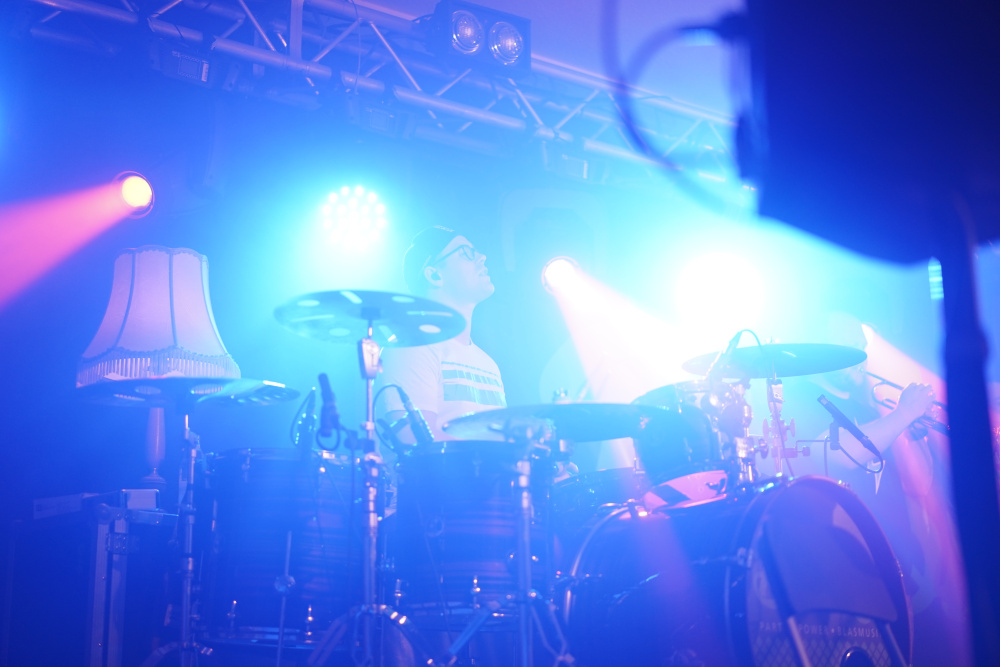 Schlagzeuger an den Drums der Partyband in blauem Licht